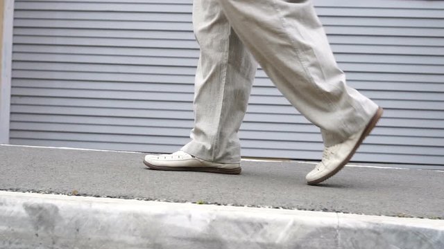 Shot of men feets in shoes walking on tile road. Urban Environment