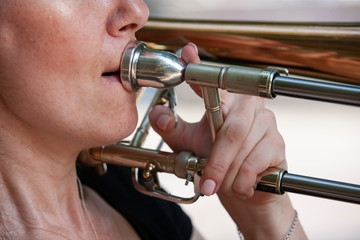 Obraz premium Girl learning to play trombone. Portrait of a girl on a background of a city park park.