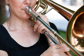 Obraz premium Girl learning to play trombone. Portrait of a girl on a background of a city park park.