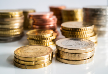 Several Euro coins stacked per value. Twenty, ten and five, one and two euros