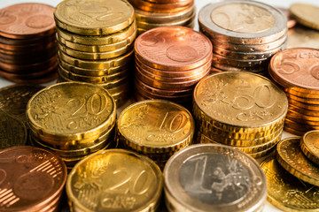 Several Euro coins stacked per value. Twenty, ten and five, one and two euros