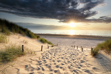 path on sand to North sea beach at sundown