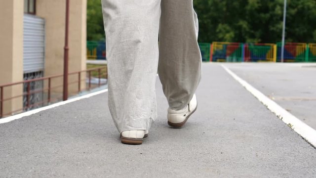 Shot of men feet in shoes walking on tile road. Urban Environment