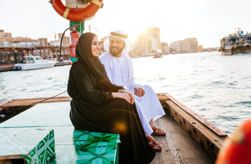 Happy couple spending time in Dubai. man and woman wearing traditional clothes taking a cruise on...