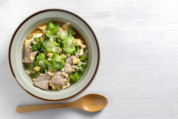 top view of stir fried luffa with pork in a ceramic dish, copy pace. delicious and healthy homemade...