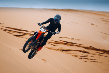 Motorcyclist on a cross-country motorcycle jump from the sand dune