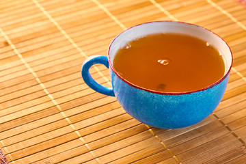 Blue cup of tea isolated on a bamboo table background 