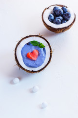 Blue matcha smoothie with berries and fruits in a coconut.
