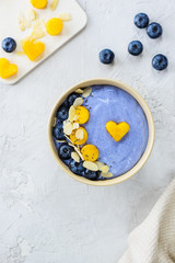 Blue matcha smoothies with berries and fruits in a bowl on a gray.