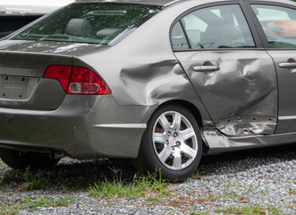 Damage to the rear panel, door and tire of a gray car due to an automobile accident