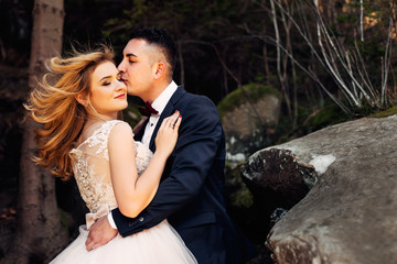 the newlyweds gently embrace, close their eyes and smile. rocks.