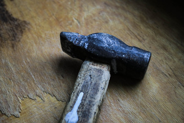Old hammer on a wooden board