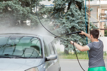 A man washes his car in a self-service sink in the summer outdoors