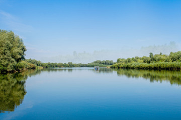 Fototapeta na wymiar Blue beautiful sky against the background of the river. Clouds are displayed in calm water. On the horizon, the green bank of the Dniester, place for fishing