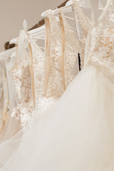 Assortment of dresses hanging on a hanger on the background studio. Fashion wedding trends. Interior of wedding shop
