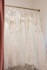 Assortment of dresses hanging on a hanger on the background studio. Fashion wedding trends. Interior of wedding shop