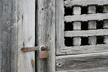 antique wooden window closed by an old rusty lock