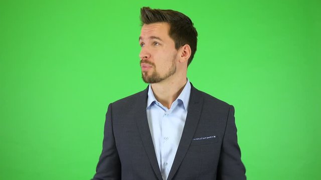 A young handsome businessman talks to the camera, throwing out his hands helplessly - green screen studio