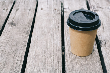 Mockup of coffee paper cup on brown wooden background. Copy space