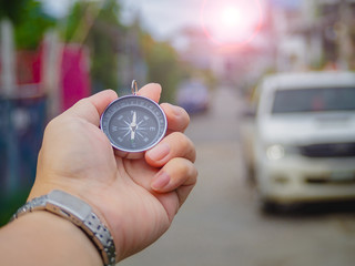 Hand holding navigate compass on street to find the target.