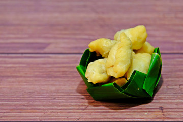 Pan Klib, Fried chicken dumplings in banana leaf bowl on wooden table.