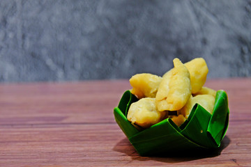 Pan Klib, Fried chicken dumplings in banana leaf bowl on wooden table with concrete background.