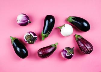 Fresh eggplants of different color and variety on a pink background