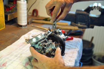 motorcycle carburetor. Automotive Carburetor Repair. Male Using A tong To Rebuild A Carburetor On A Workbench. Mechanic man checking carburetor of motorcycle. Repair. Maintenance and fixing concept.  