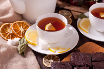A cup of tea with lemon and pieces of homemade chocolate cake on a wooden kitchen tray. Fresh homemade cakes. Chocolate biscuit. Brownie. Tea party.