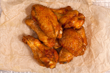 Fried juicy chicken wings marinated with honey, soy sauce and spices on a paper background. Asian recipe, top view, close-up.