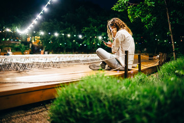 Rear view young woman sitting on bench using smart phone