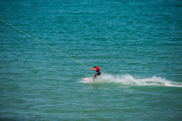 Wakeboarding. Fit attractive wakeboarder looking straight ahead while riding over the surface of water