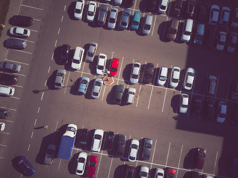 A view from above to the process of car parking. Heavy traffic in the parking lot. Searching for spaces in the busy car park. Parking advice. Cruising for parking in busy business center