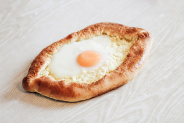 Homemade Ajarian Khachapuri with Suluguni Cheese Filled with a  Egg and Melted Butter Close Up on the white wooden background