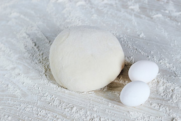 dough with flour and eggs on a white background; Dough ready for cooking