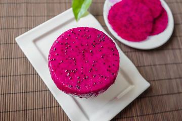 A plate of seductive red dragon fruit placed on a tablecloth top view