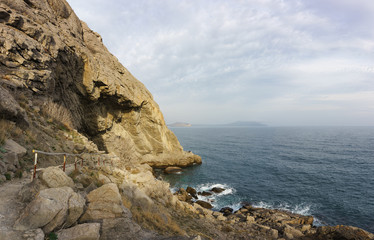 People stand on a ledge of rock near the grotto Chaliapin. Calm Black sea at the foot of the...