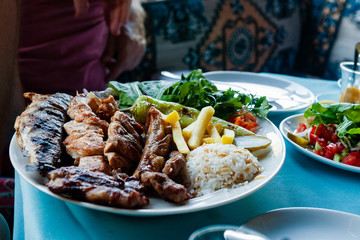 Traditional turkish dish with fried fish, chicken, lamb and vegetables on a table in an outdoor cafe