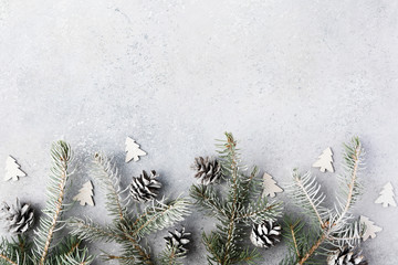 Christmas background with a gifts, fir tree branches, cones and snow on gray concrete table. Christmas composition. Flat lay. Top view