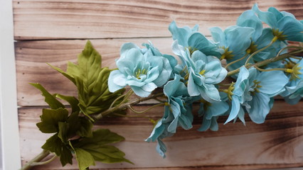 Plastic fake flowers on wooden wall background