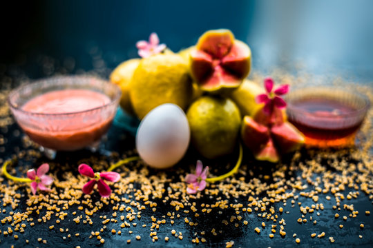 Treatment of dry skin with the help of face mask on a wooden surface consisting of honey, guava pulp, egg yolk, and some oatmeal, well mixed in a glass bowl along with raw ingredients.