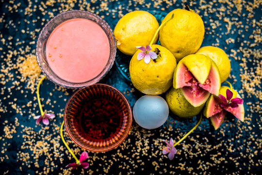 Treatment of dry skin with the help of face mask on a wooden surface consisting of honey, guava pulp, egg yolk, and some oatmeal, well mixed in a glass bowl along with raw ingredients.