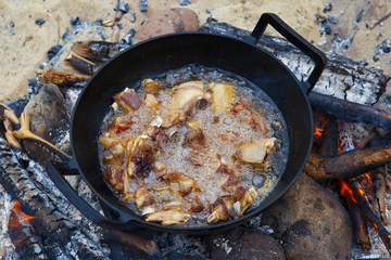 Pieces of lamb are fried in boiling oil in a pan on the fire. As a stage in the preparation of traditional pilaf.