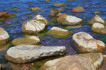 Large stones in the blue water of the sea.