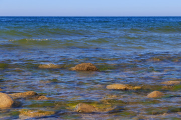 Large stones in the blue water of the sea.