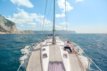 white yacht with sail set goes along the island on a hot day. blue sea, blue sky. Crimea. on board a young couple in love. the bride and groom. wedding boat trip