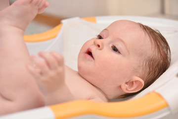 Pretty three months baby girl taking a bath by her mother at home, european child.
