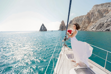 white yacht with sail set goes along the island on a hot day. blue sea, blue sky. Crimea. on board a young couple in love. the bride and groom. wedding boat trip