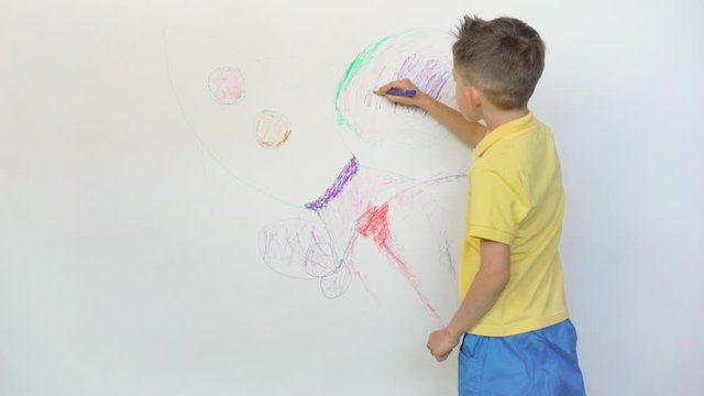 Cute little child drawing rocket on white wall