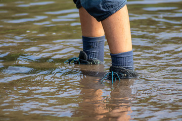 Junge watet mit nassen Schuhen und nassen Socken durch Hochwasser nach einer Überschwemmung mit...